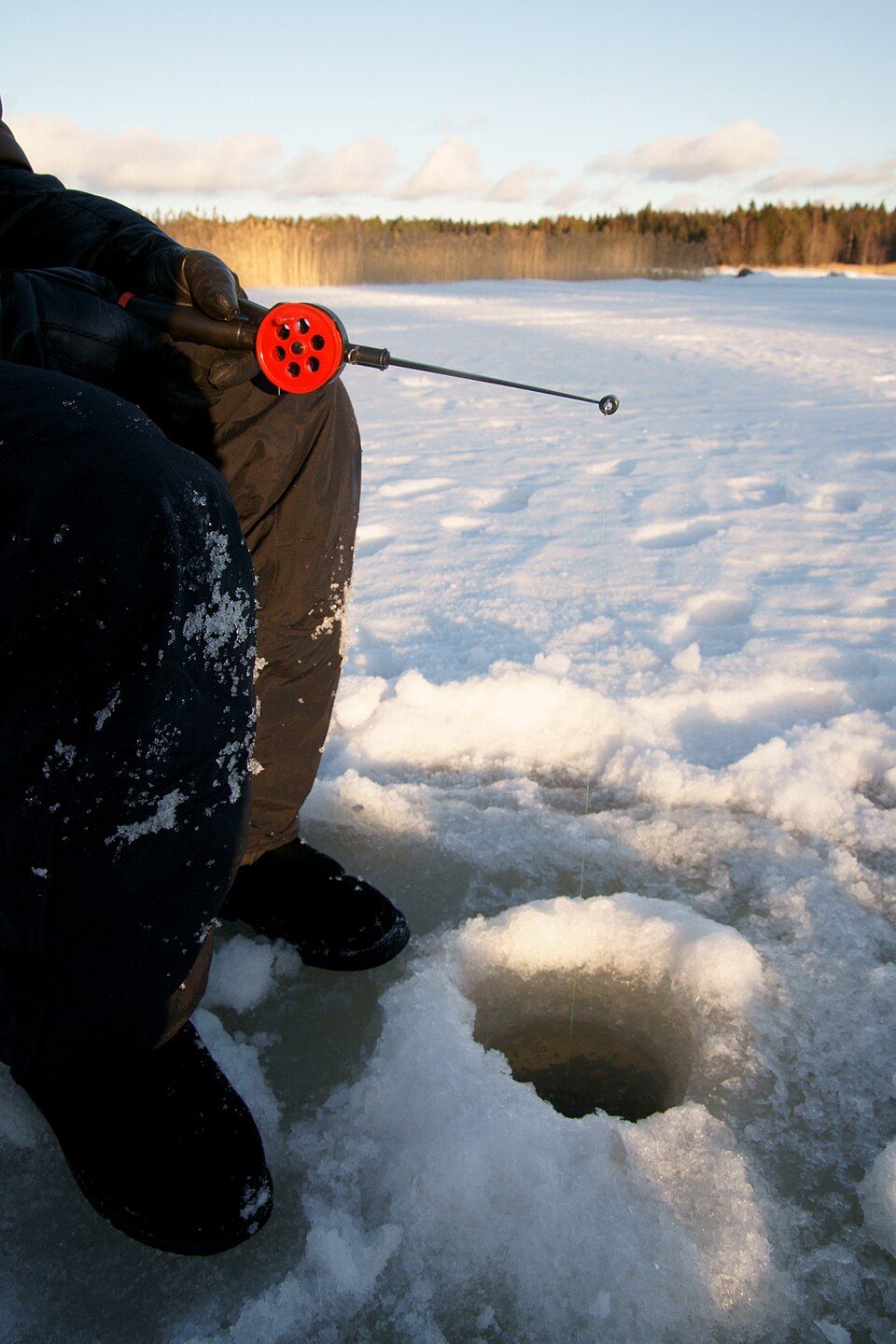 ice fisher on frozen water